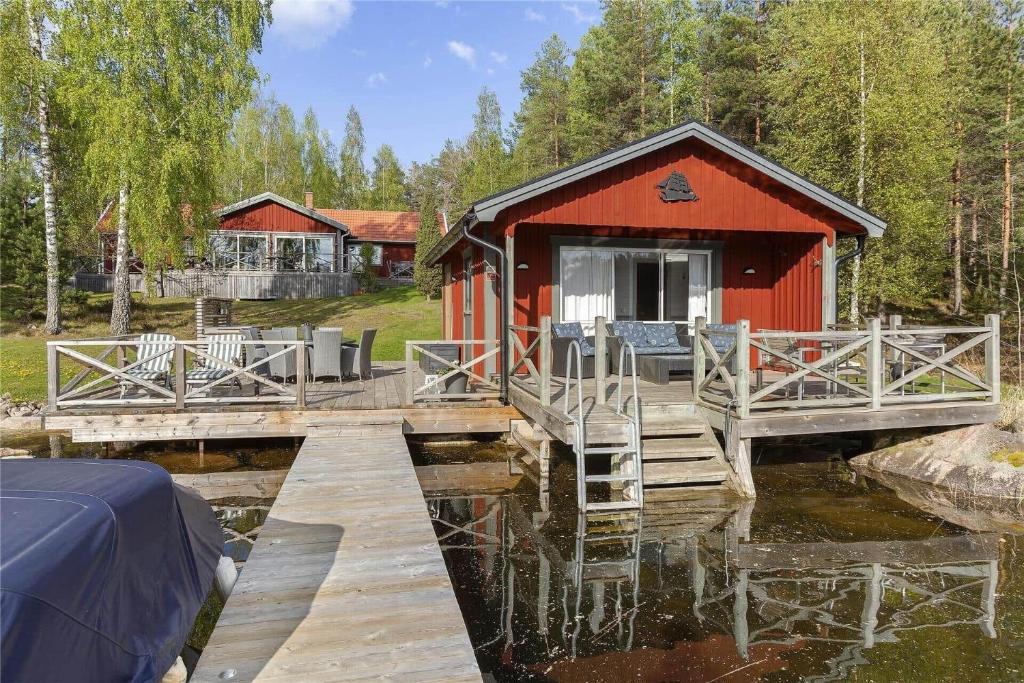 a red cabin with a dock next to a body of water at OGO368-Boxholm-Tingkullanaes-6 in Blåvik