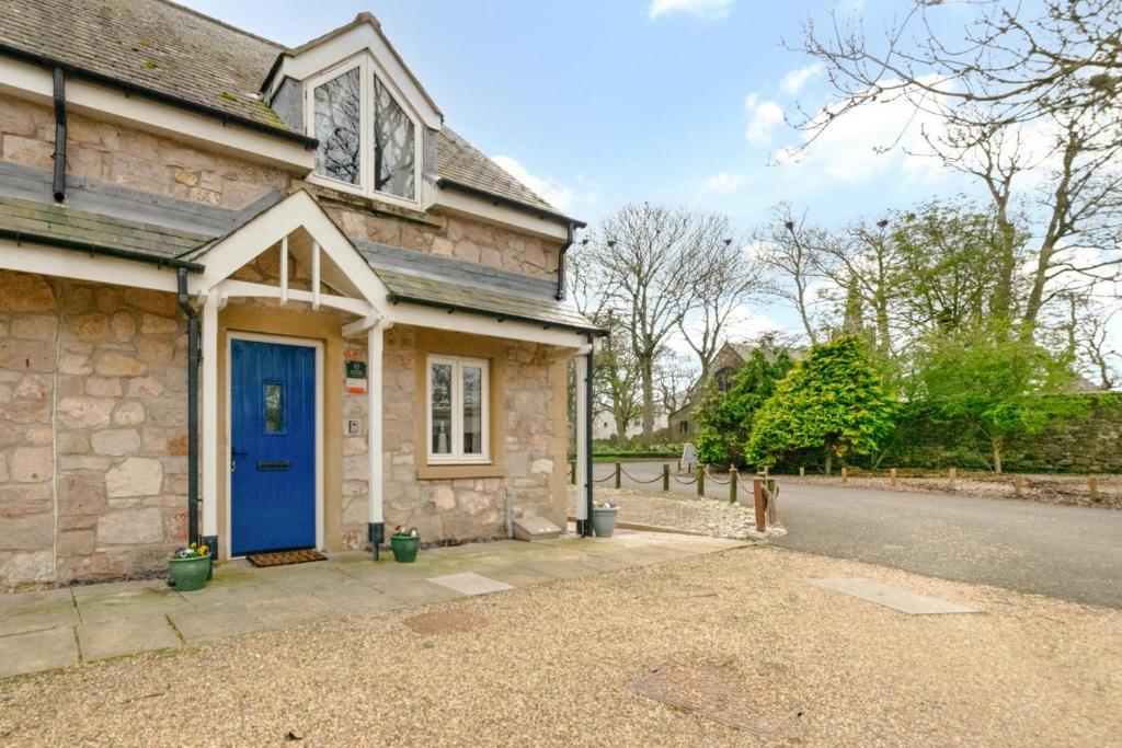 une maison en pierre avec une porte bleue dans une rue dans l'établissement Cuthbert Cottage, à Beadnell