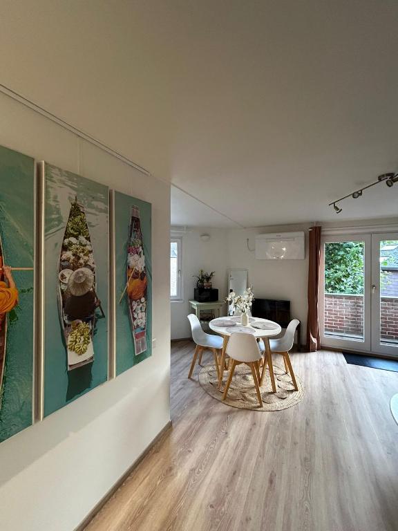 a dining room with a table and chairs and paintings at Centre de LLN - Appartement rénové - Parking gratuit in Louvain-la-Neuve