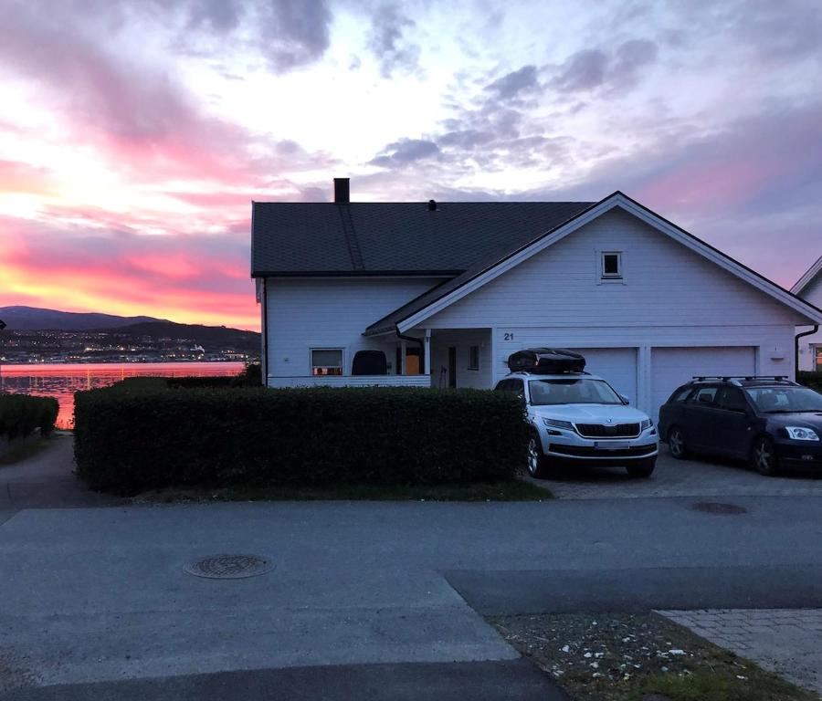 ein weißes Haus mit zwei Autos davor geparkt in der Unterkunft Unique house next to the sea in Tromsø