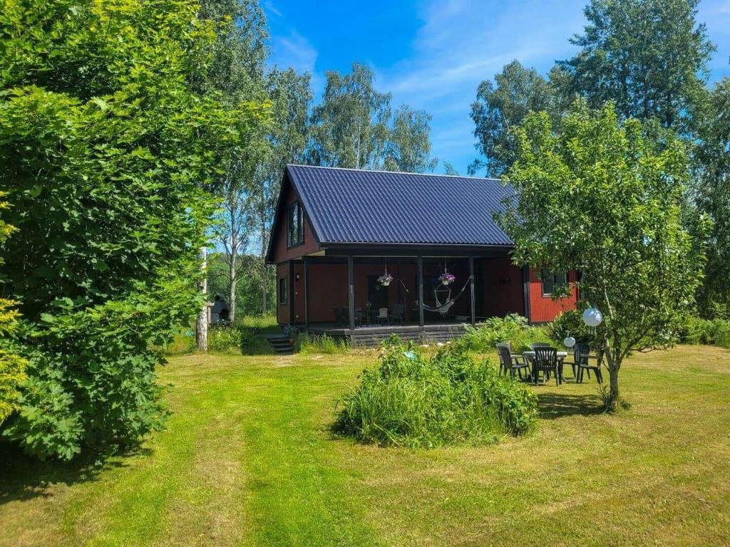 a red barn with a table and chairs in a yard at SOD691-Stavsjoe-Kila-Skogsby-Nygarden-3 in Stavsjo