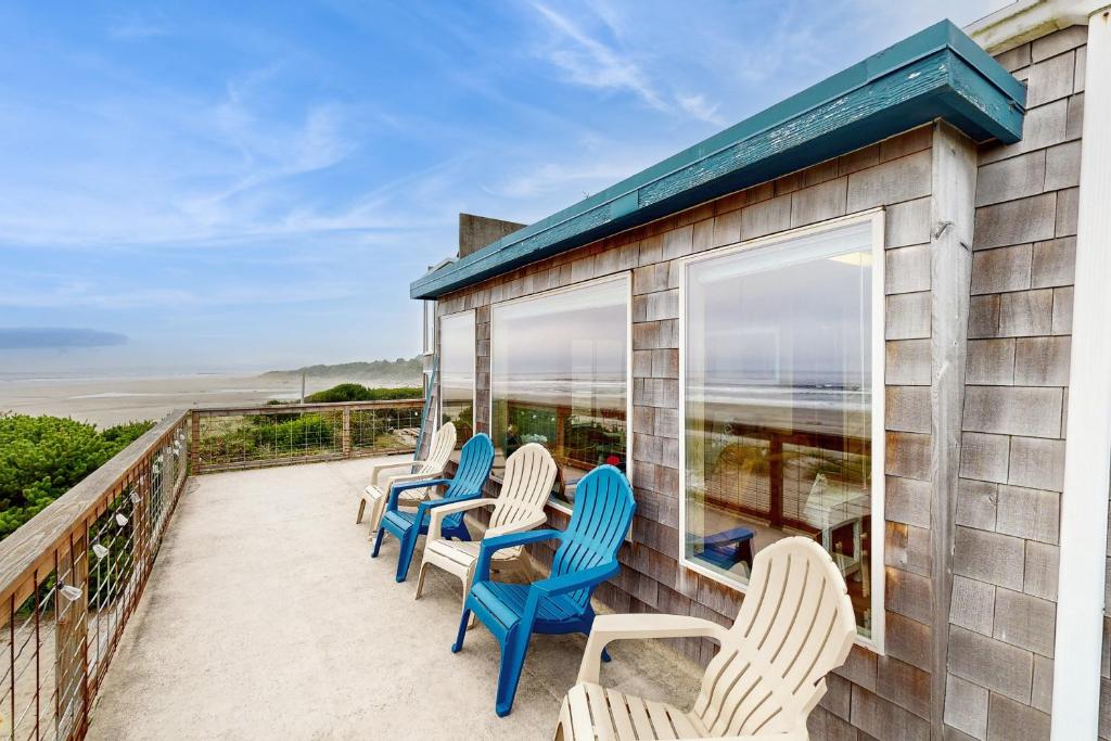 a row of chairs on a balcony with a view of the ocean at A Wave From It All in Rockaway Beach