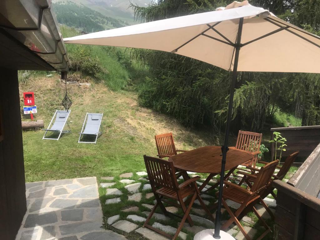 a table and chairs with an umbrella on a patio at Chalet Alma in Champoluc