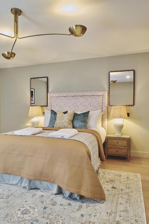 a bedroom with a large bed with two mirrors at The Barn Hotel in Meriden