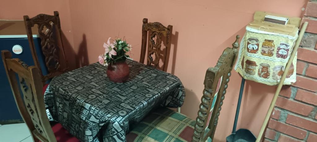 una mesa y sillas con un jarrón de flores. en Cabaña Algarrobo el yeco, en San Antonio