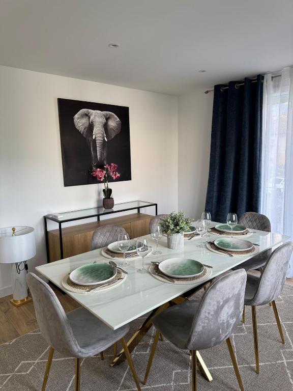 Un comedor con una mesa con sillas y una imagen de un elefante. en Longchamps 2 - Grand appartement 73m2 neuf spacieux, en Aix-les-Bains