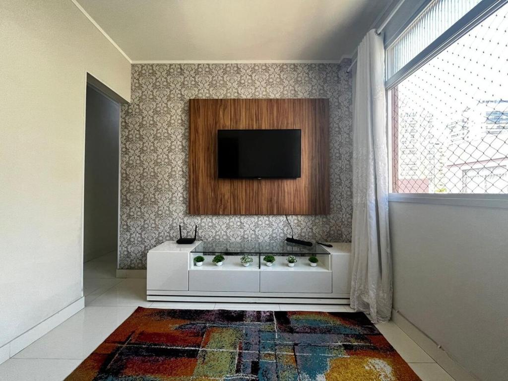 a living room with a television on a wall at Itapuã - 4 Minutos da Praia - Apartamento Espaçoso - 3 Quartos in Vila Velha