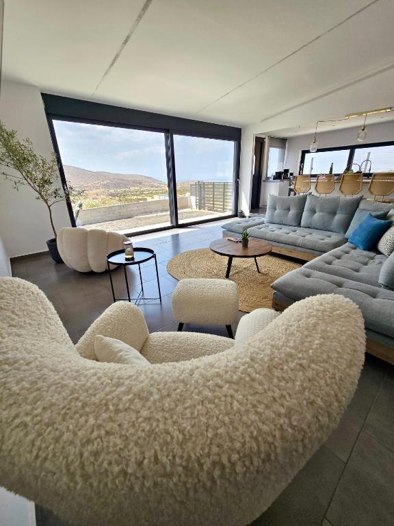 a living room with couches and chairs and a large window at Aquarius Luxury Suites in Ólimbos