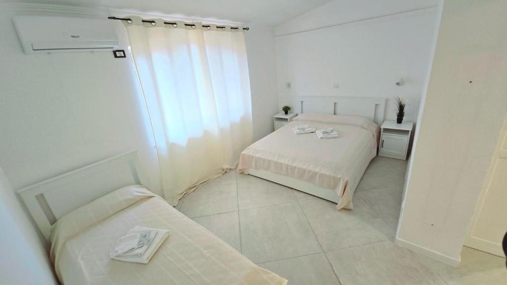 a white room with two beds and a window at Hotel paradiso in Scalea