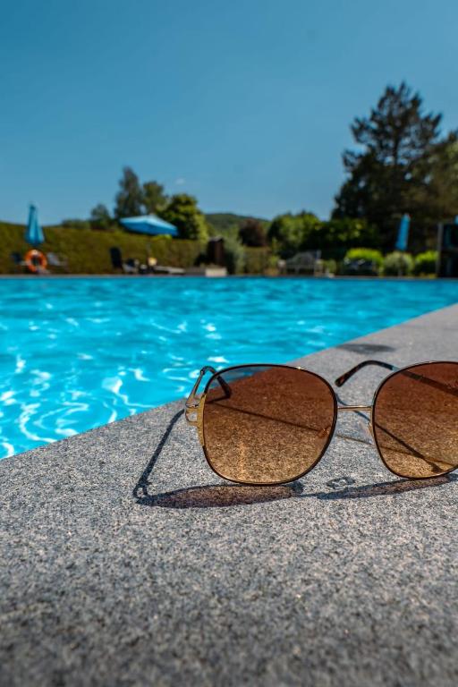 a pair of glasses sitting next to a swimming pool at L'apais'Han in Rochefort