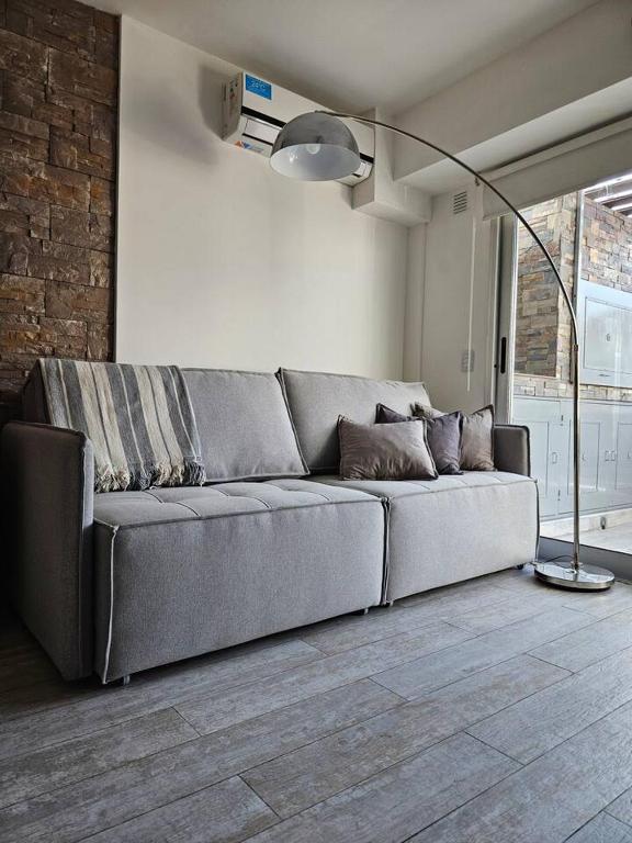 a gray couch in a living room with a lamp at Dto nueva cordoba in Barraquero