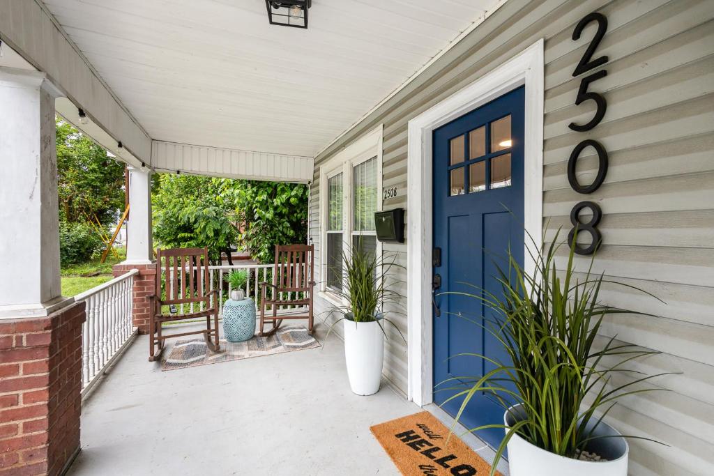 a porch with a blue door and two plants at Walkable City Trendy Hideout for Foodies - 3BR-2BA in Charlotte