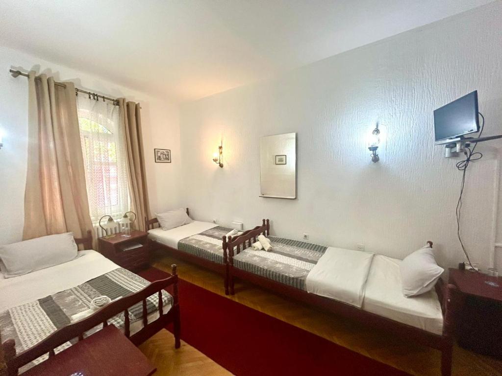 a room with two beds and a tv on the wall at Bulevar in Valjevo
