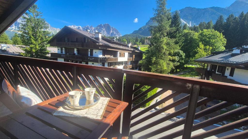 a wooden balcony with a table with cups on it at Apartment 5 Torri, tipico attico a Cortina in Cortina dʼAmpezzo