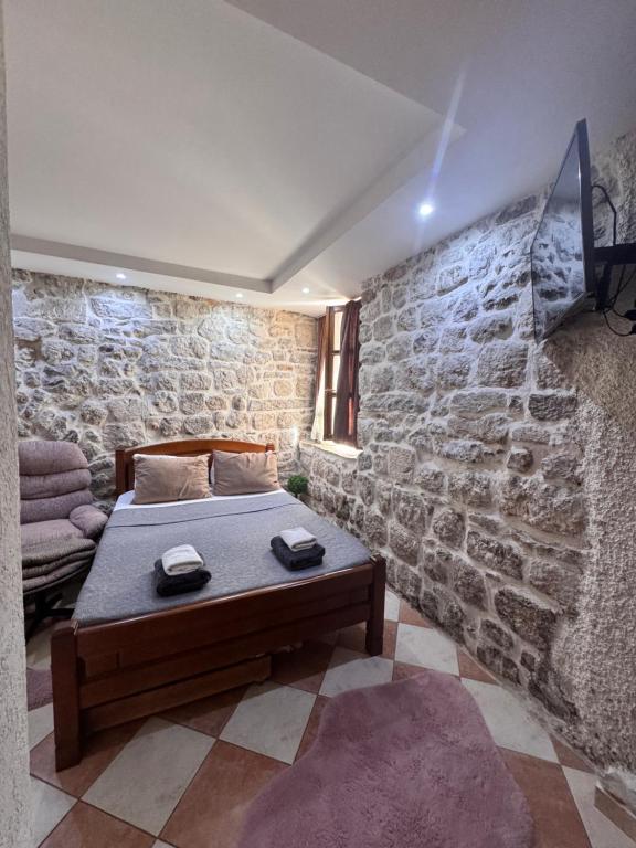a bedroom with a bed and a stone wall at Last Summer hotel Kotor in Kotor