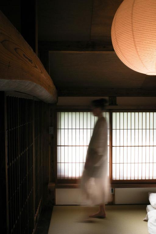 a person is walking in a room with windows at Akitsu Ryokan in Maibara