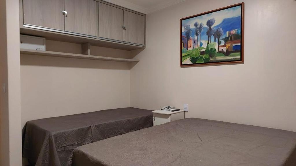 a room with two beds and a painting on the wall at Flat confortável e completo a 800m do Hot Park in Rio Quente