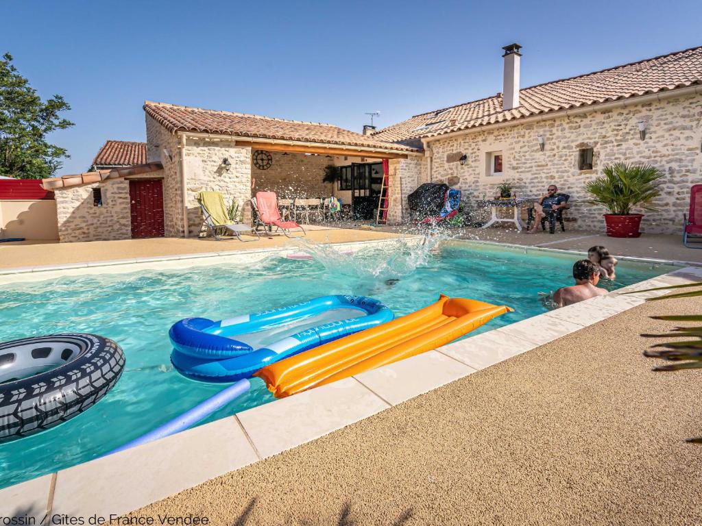 a boy is playing in a swimming pool with a slide at Maison rénovée pour 14 pers avec piscine chauffée, jardin, baby-foot, proche Puy du Fou et La Rochelle - FR-1-426-362 in LʼHermenault