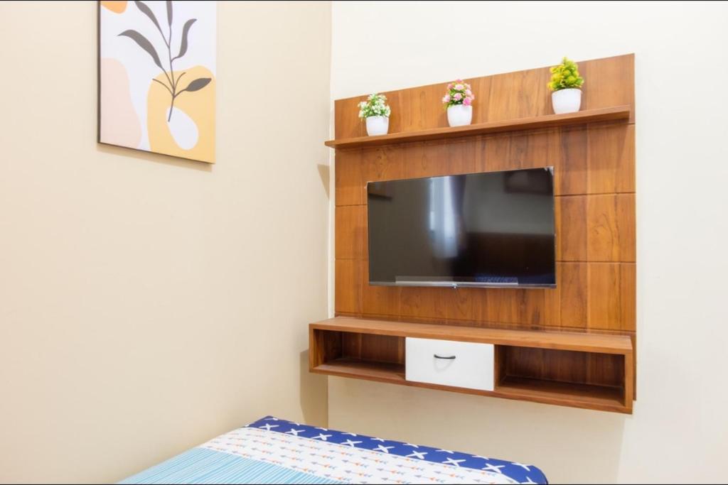 a living room with a flat screen tv on a wall at Kost Putri Exclusive Orchidee in Jatingaleh