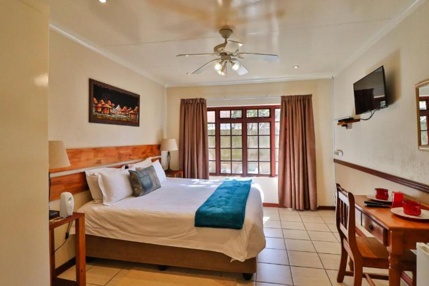 a bedroom with a bed and a desk and a window at The Link Accommodation in Kempton Park