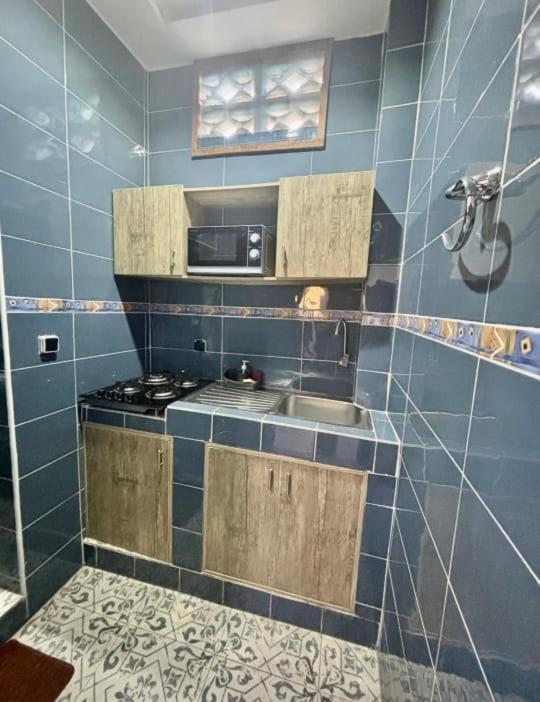 a blue tiled kitchen with a sink and a microwave at Bisola Residences in Cotonou