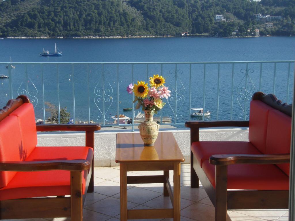 2 sillas y una mesa con un jarrón de flores en el balcón en Agnantema, en Skiathos