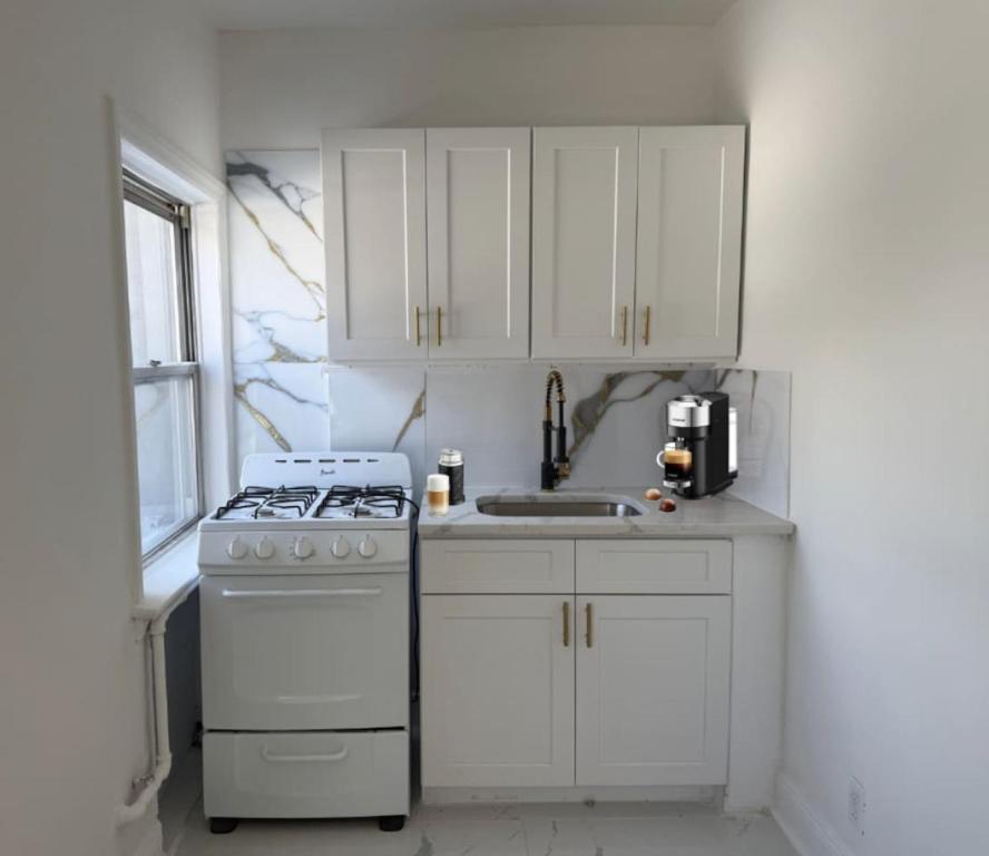 a white kitchen with a stove and a sink at Scandinavian Style 1 Bd 15 min to nyc parking in Guttenberg