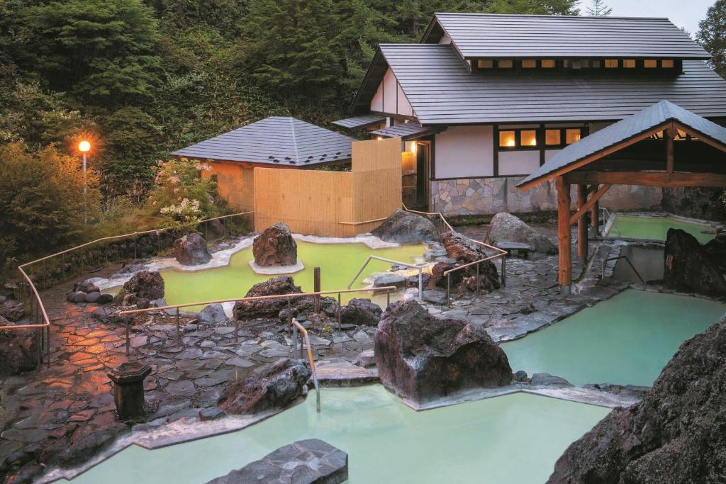 a pool of water in front of a house at Manza Kogen Hotel in Tsumagoi