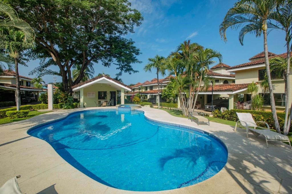 a swimming pool in a yard with palm trees at Gorgeous Three Bedroom Townhouse in Coco