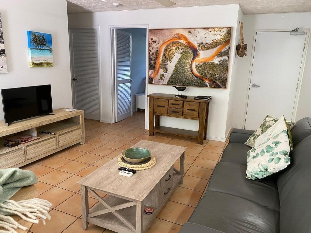 a living room with a couch and a tv at Baden 26 - Rainbow Shores - Swimming pools - Tennis court - Walk to beach in Rainbow Beach