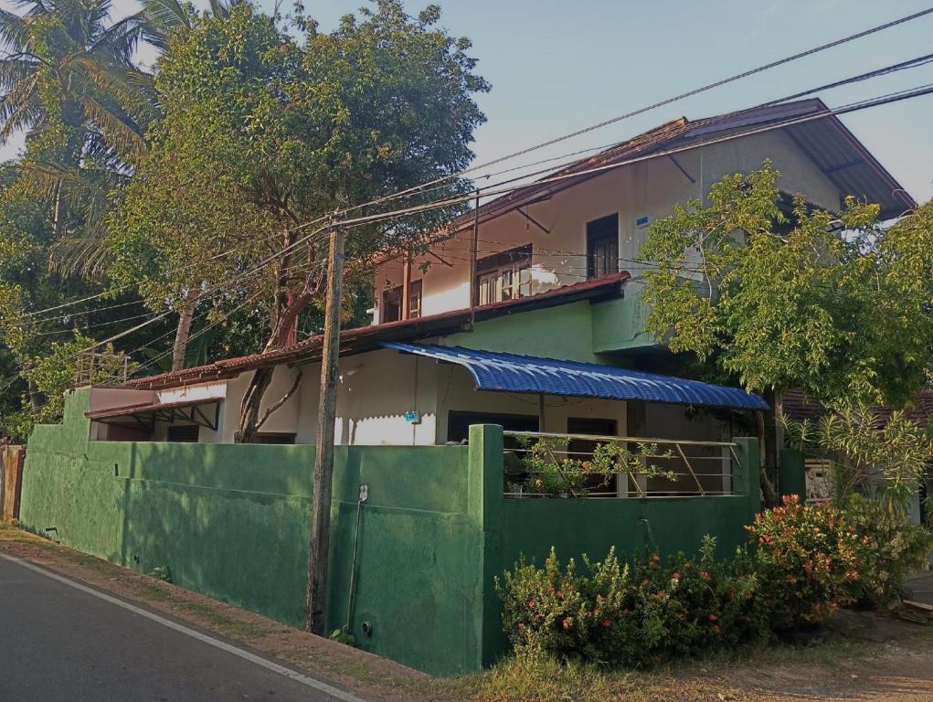 a house with a green fence in front of it at Aura Home House Hostel in Polonnaruwa