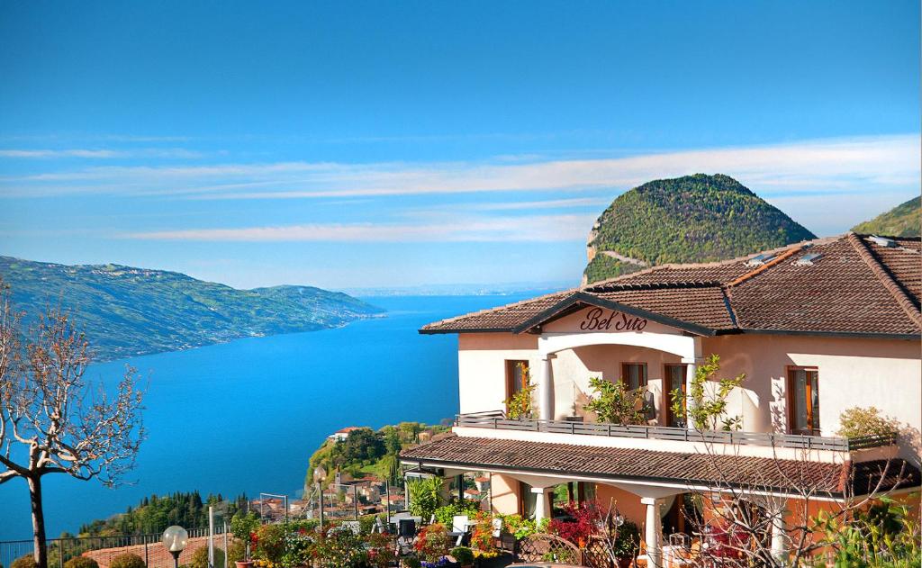 un edificio su una collina con vista sull'acqua di Hotel Garni Bel Sito a Tremosine Sul Garda