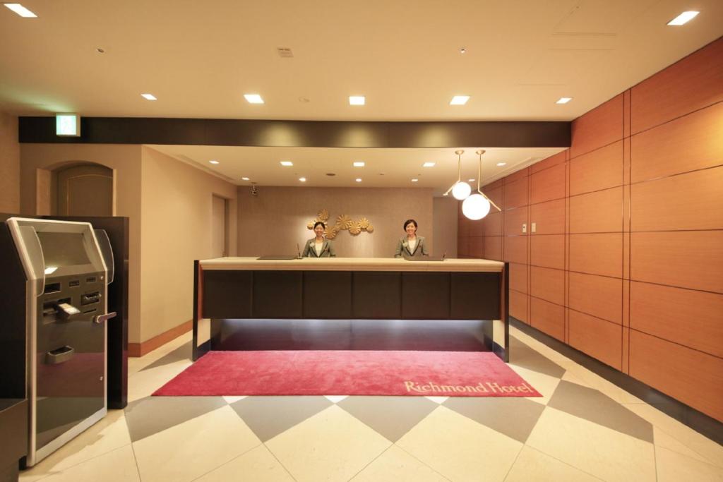 twee mensen in een kamer met een rood tapijt bij Richmond Hotel Tokyo Mejiro in Tokyo