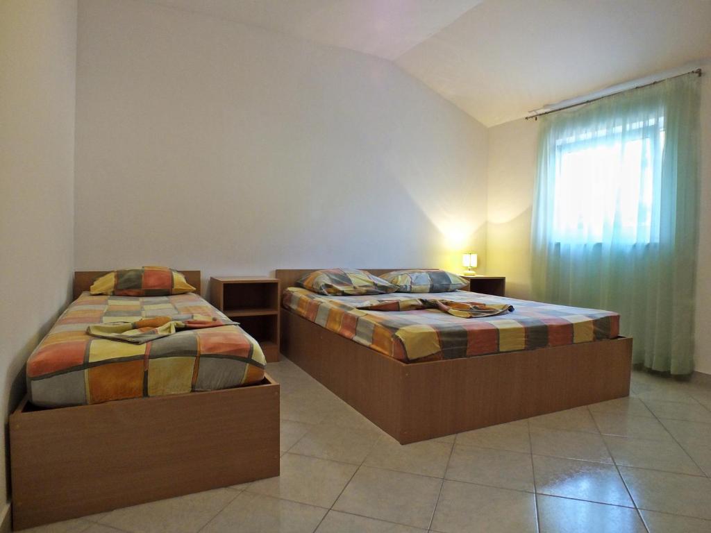 a bedroom with two beds and a window with a curtain at Apartments Radic in Rogoznica