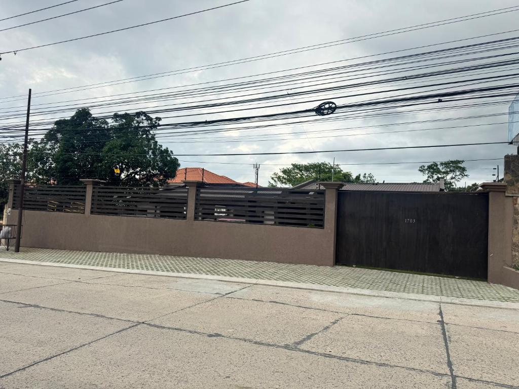 a house with a fence and a gate with power lines at Gran Hostal Sula in San Pedro Sula