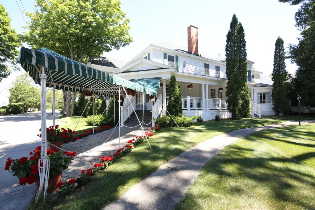 une maison blanche avec un auvent dans la cour dans l'établissement Colonial Inn Harbor Springs, à Harbor Springs