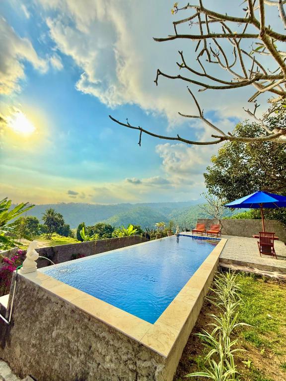 una piscina con dos sillas y una sombrilla en Villa Marlinda, en Narmada