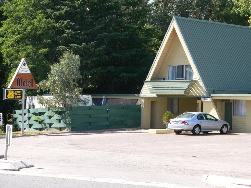 a car parked in a parking lot in front of a house at Millers Cottage Motel in Wangaratta