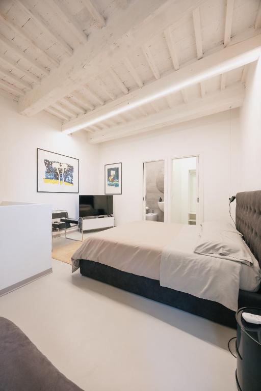 a white bedroom with a large bed and a television at Duplex d'Art - Centro Storico di Arezzo in Arezzo