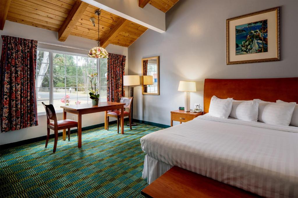 Cette chambre comprend un lit, un bureau et une table. dans l'établissement Butterfly Grove Inn, à Pacific Grove