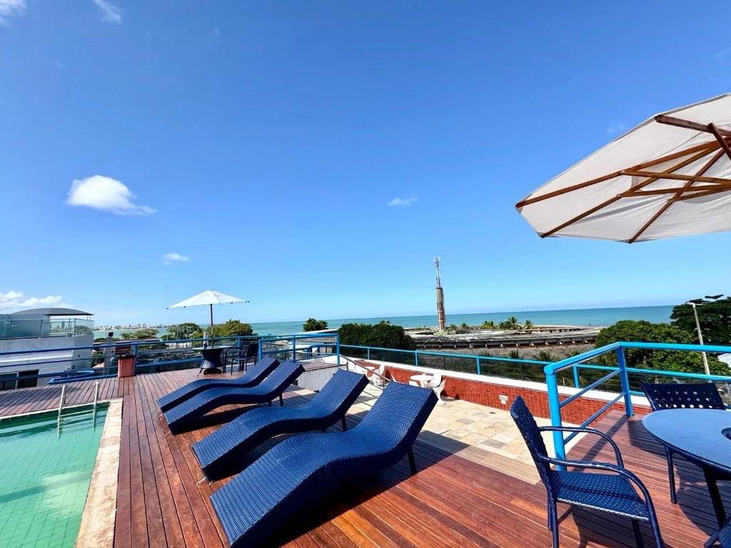 a deck with chairs and a table and an umbrella at Victory Tambaú in João Pessoa