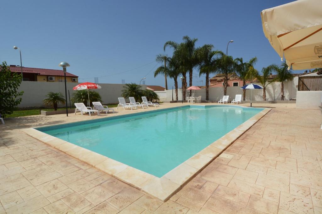 una gran piscina con sillas y sombrillas en B&B La Castellana, en Marina di Ragusa