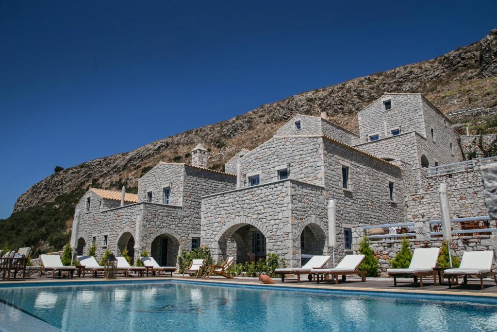un complexe avec une piscine entourée de chaises et un bâtiment dans l'établissement Εn Plo Luxury Suites, à Karavostasion