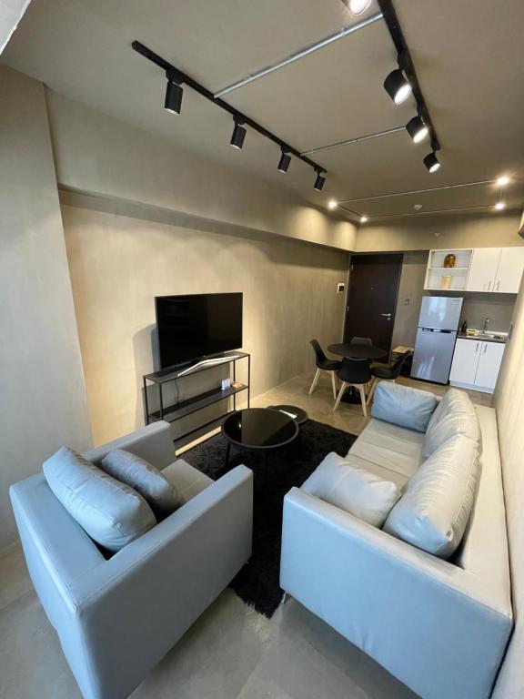 a living room with two white couches and a television at 1-BR Luxury Condo, Centrio Tower, Ayala Malls in Cagayan de Oro