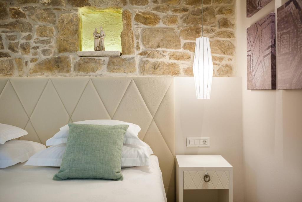 Un dormitorio con una cama con una pared de piedra. en Balatura The Fine Bed&Breakfast Split, en Split