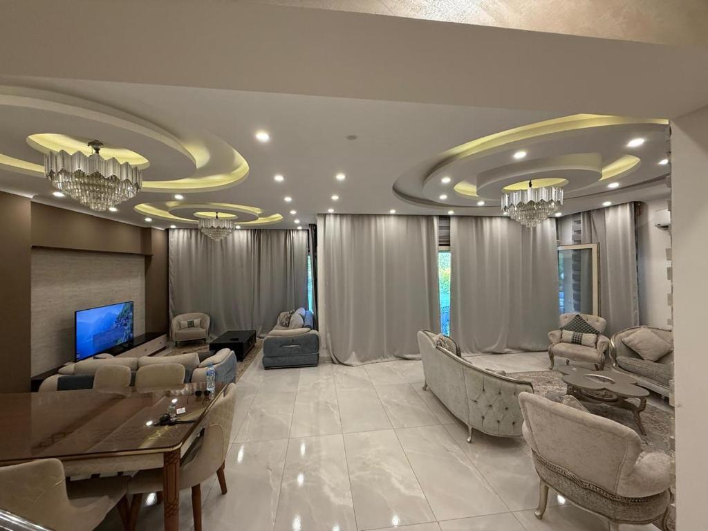 ein Wohnzimmer mit einer Couch und einem Tisch und Stühlen in der Unterkunft فيلا مع حمام سباحه وجاردن 0306-888-0106 in Kairo