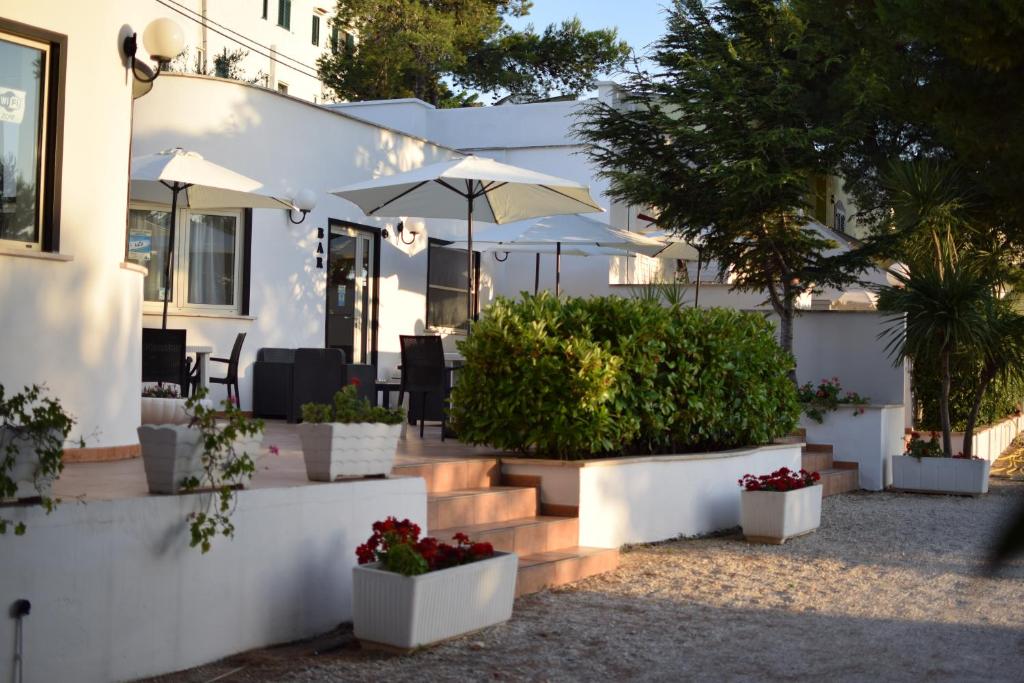 una casa bianca con alcune piante e ombrelloni di Argeste Club Vacanze a Vieste