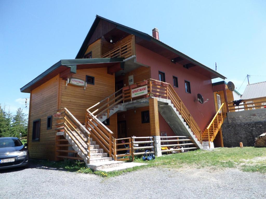 a house with wooden stairs on the side of it at Apartments Anđela in Žabljak