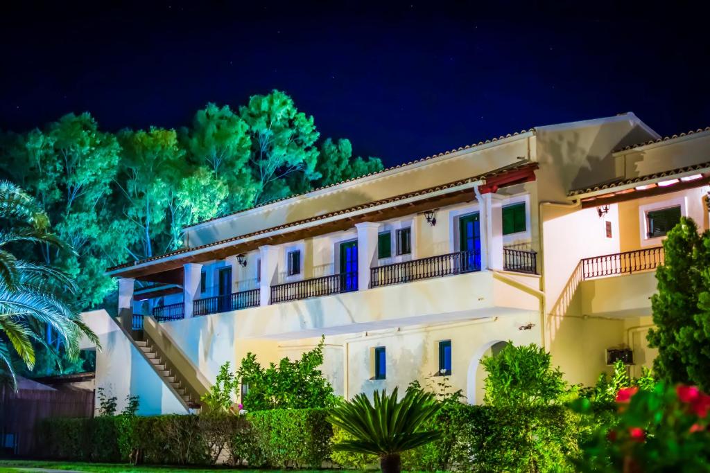 un gran edificio blanco con puertas azules por la noche en Marini Apartments, en Moraitika