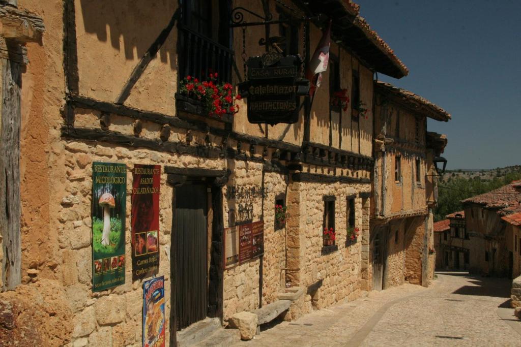 un antiguo edificio de piedra con flores al lado de una calle en Hotel Rural Calatañazor, en Calatañazor